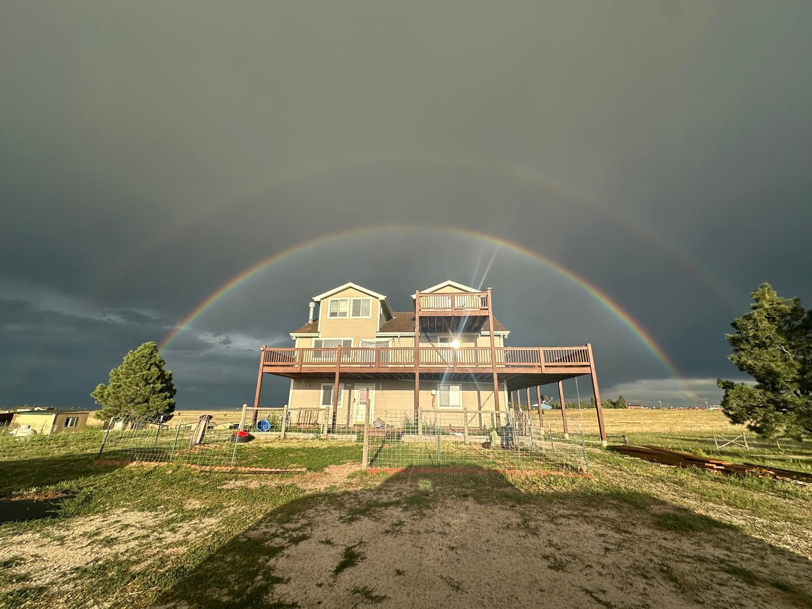 A rainbow over the GoRunGo Ranch farmhouse and pasture