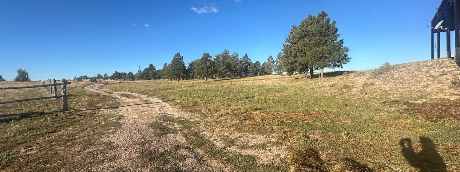 Panorama of the open 35-acre pasture with fence line and trees